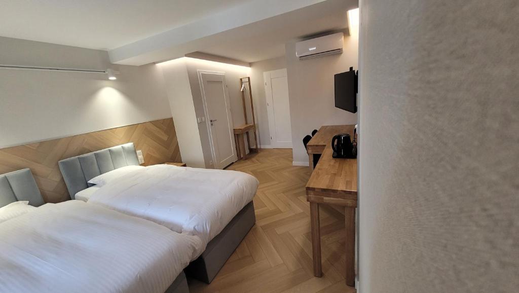 Cette chambre comprend deux lits et un bureau. dans l'établissement Hotel & Restauracja Wróblewscy, à Karniewo