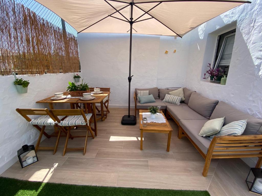 a patio with a couch and a table and an umbrella at Renovated nice private bungalow in Playa del Ingles