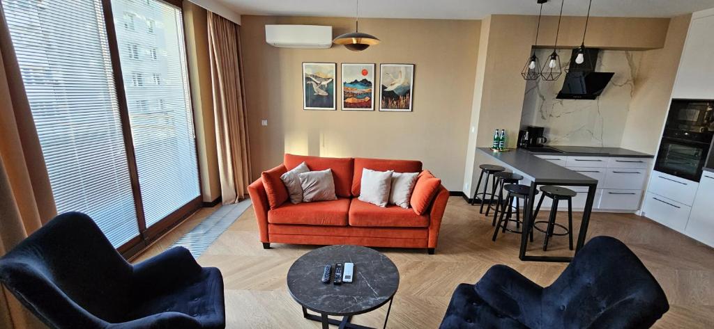 sala de estar con silla naranja y cocina en Apartament Ogrodowa Deluxe, en Varsovia