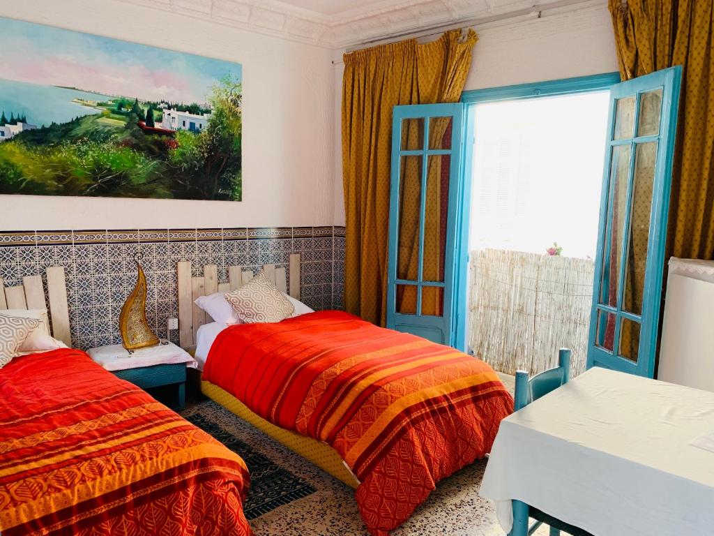 a bedroom with two beds and a window at Dar Evelyne in Mahdia