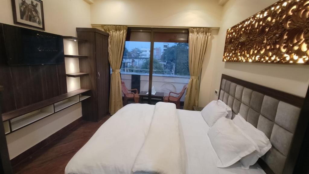 ein Schlafzimmer mit einem großen weißen Bett und einem Fenster in der Unterkunft Ratna Hotel & Banquet in Muzaffarpur