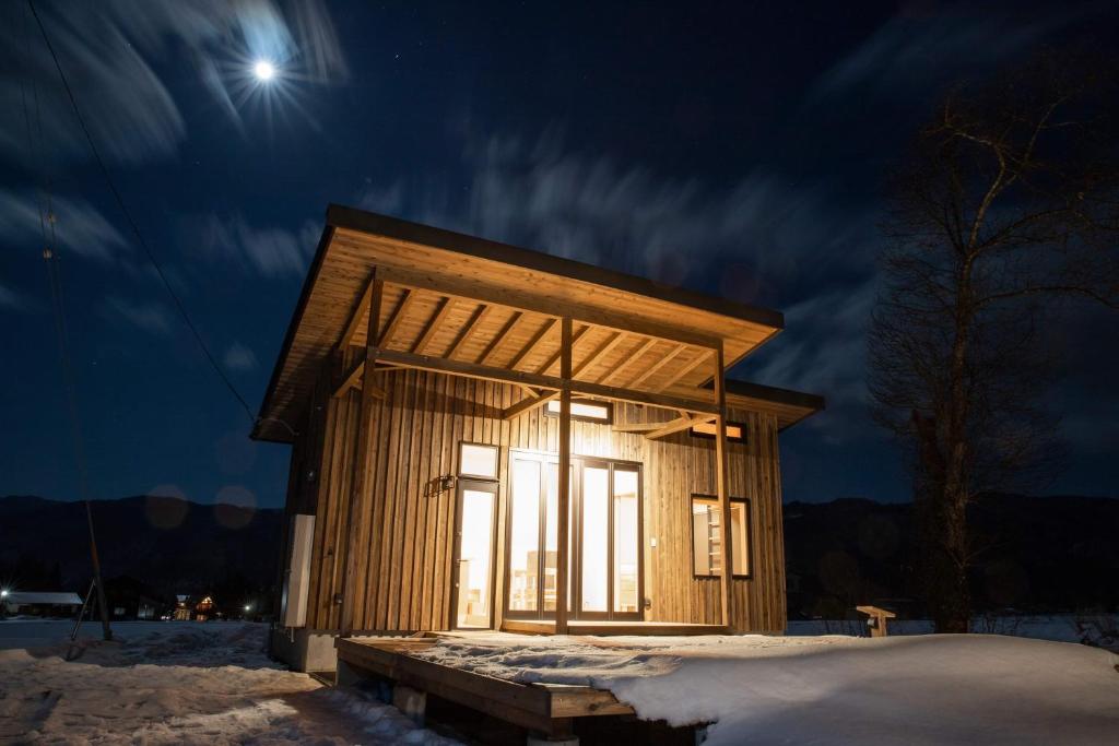 un pequeño edificio de madera en la nieve por la noche en And MOUNTAIN en Hakuba