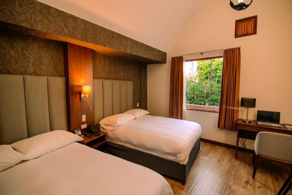 um quarto de hotel com duas camas e uma janela em La Maison d'Elise em Arequipa