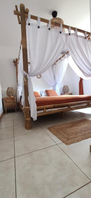 Bett in einem Zimmer mit weißen Vorhängen in der Unterkunft VILLA CAJOU DESIRADE in Baie Mahault