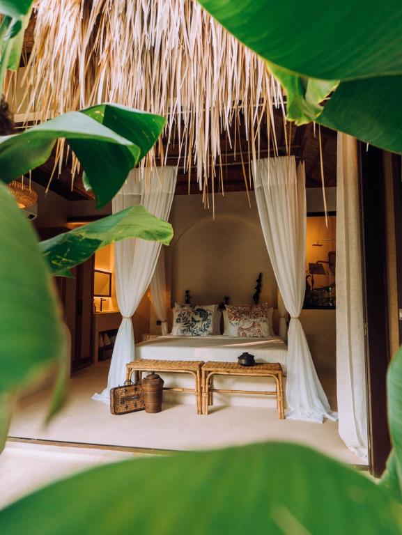 a bedroom with a bed in a room with trees at ALON Villas in El Nido