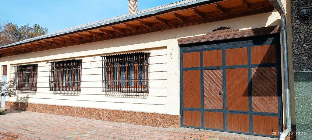 ein weißes Gebäude mit zwei Türen und zwei Fenstern in der Unterkunft INJIR Hostel in Duschanbe