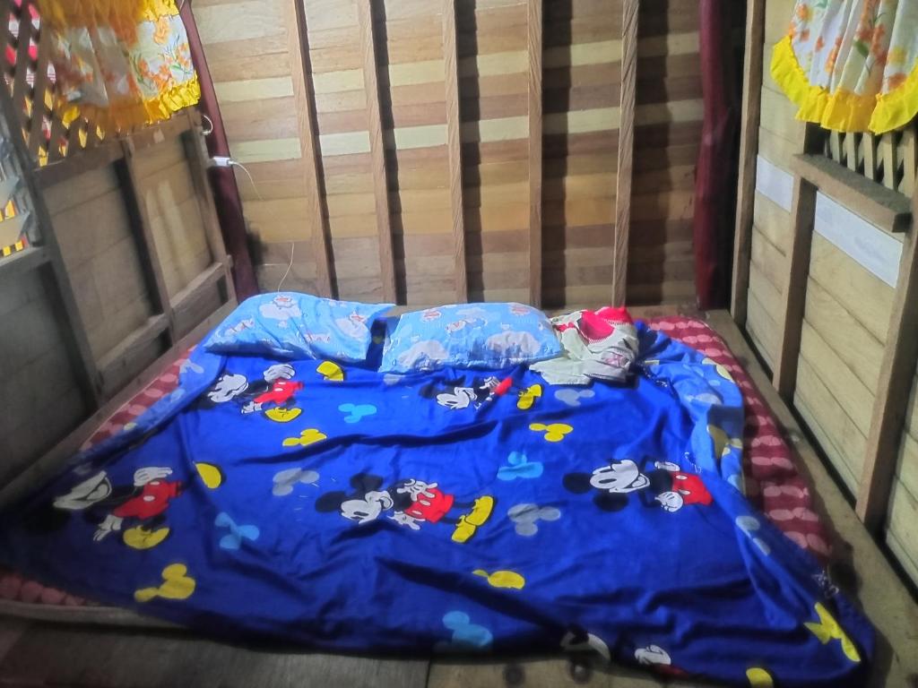 a bed with a blue blanket with hello kitty on it at Ramos Family Patungan Beach in Maragondon