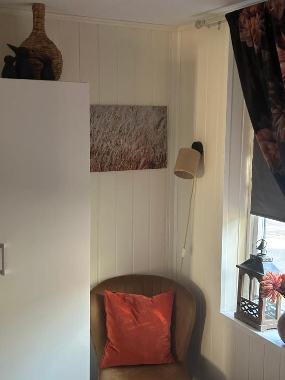 a couch with a red pillow in a room with a window at Downtown Historical House with Renovated apartments in Ålesund