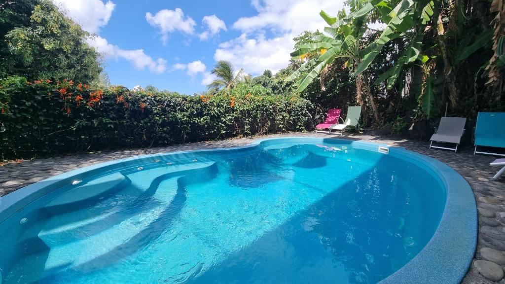 a swimming pool with a woman sitting in a chair next to it at Villa Des Remparts in Sainte-Marie