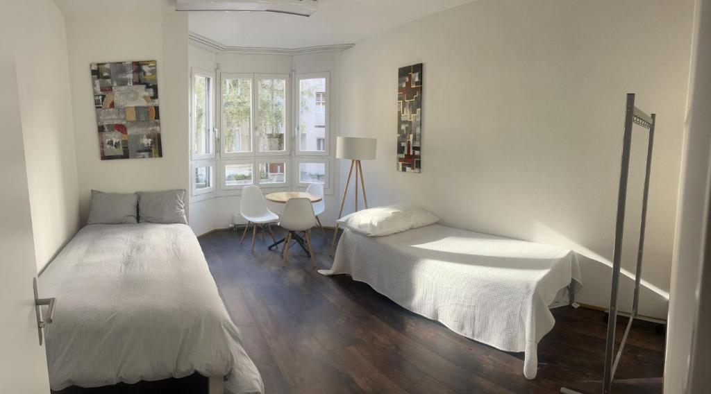 um quarto com 2 camas, uma mesa e uma janela em Basel-Stadt Gundeldingen Zimmer 403, WC in the hallway, outside the room em Basileia