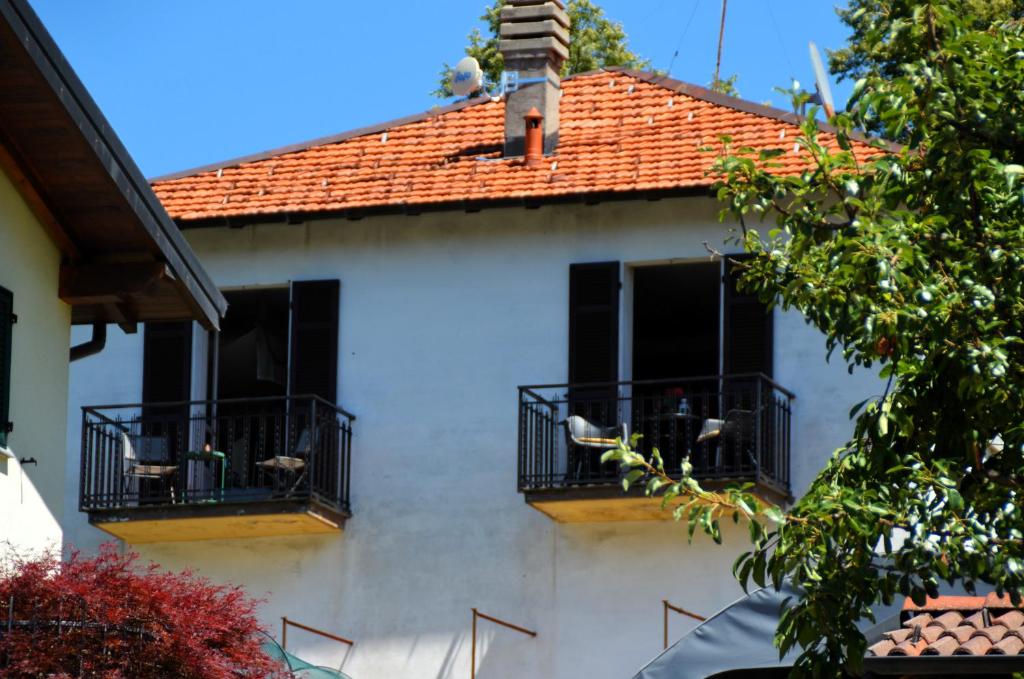 Biały dom z czarnymi oknami i czerwonym dachem w obiekcie APARTMENT for RENT BETWEEN LAGO DI COMO AND LAKE LUGANO, IN THE VILLAGE OF LAINO w mieście Laino