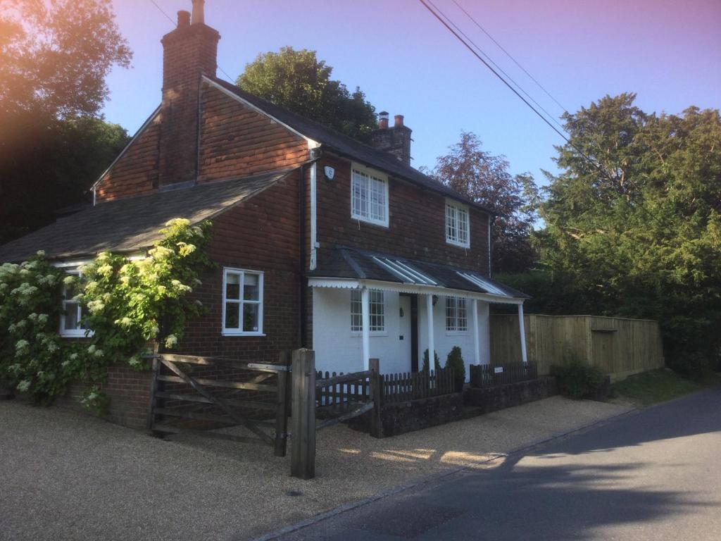 una pequeña casa de ladrillo con una puerta blanca en The Cottage, en Wadhurst