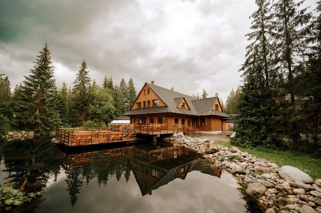 a log cabin sitting on top of a lake at Rezort pri jazere Podbanské in Pribylina