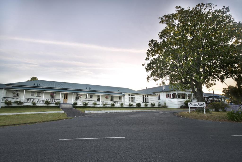 een wit gebouw met een bord ervoor bij Okoroire Hot Springs Hotel in Okoroire