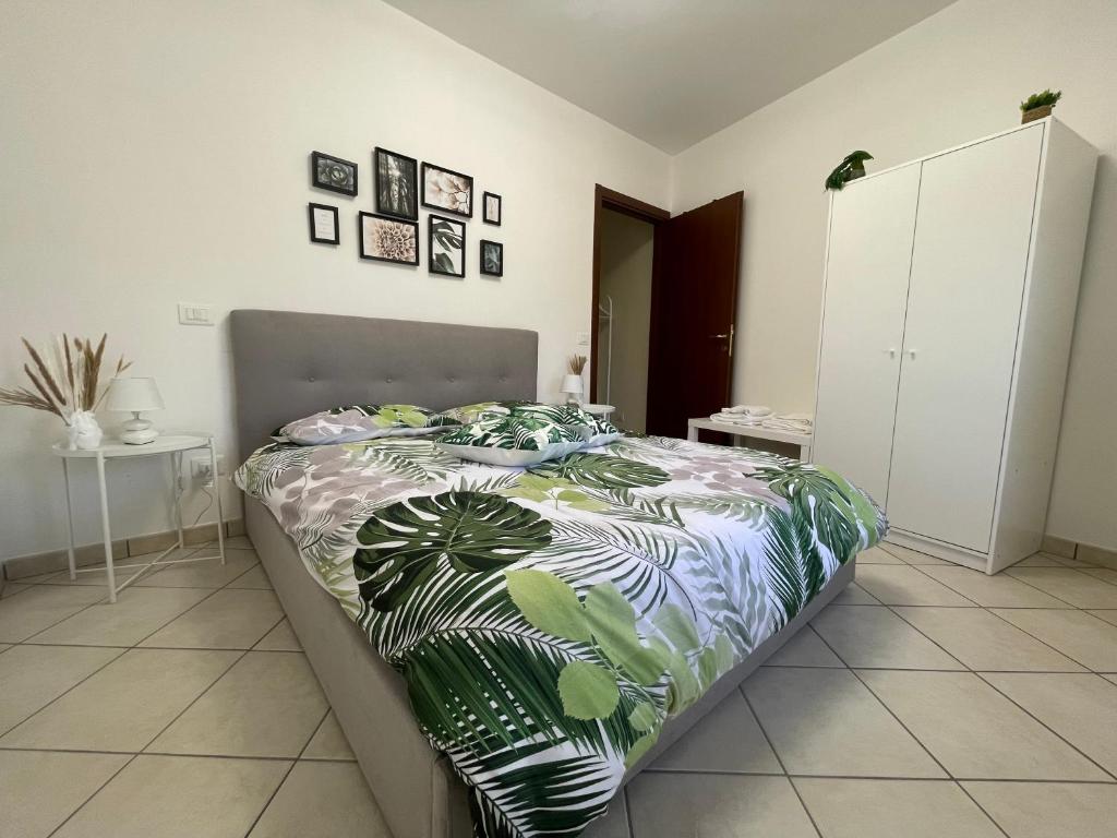 Schlafzimmer mit einem Bett mit einer grünen und weißen Bettdecke in der Unterkunft Castelli Home - Castelli Apartments in Albano Laziale
