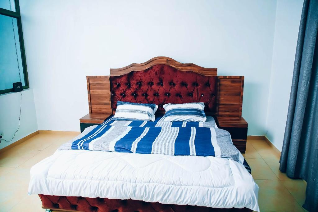 een bed met blauwe en witte gestreepte dekens en kussens bij Saint Emmanuel near Kigali Convetion center in Bugesera
