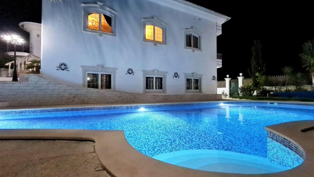 a swimming pool in front of a house at night at Silver Coast Village in Maceira