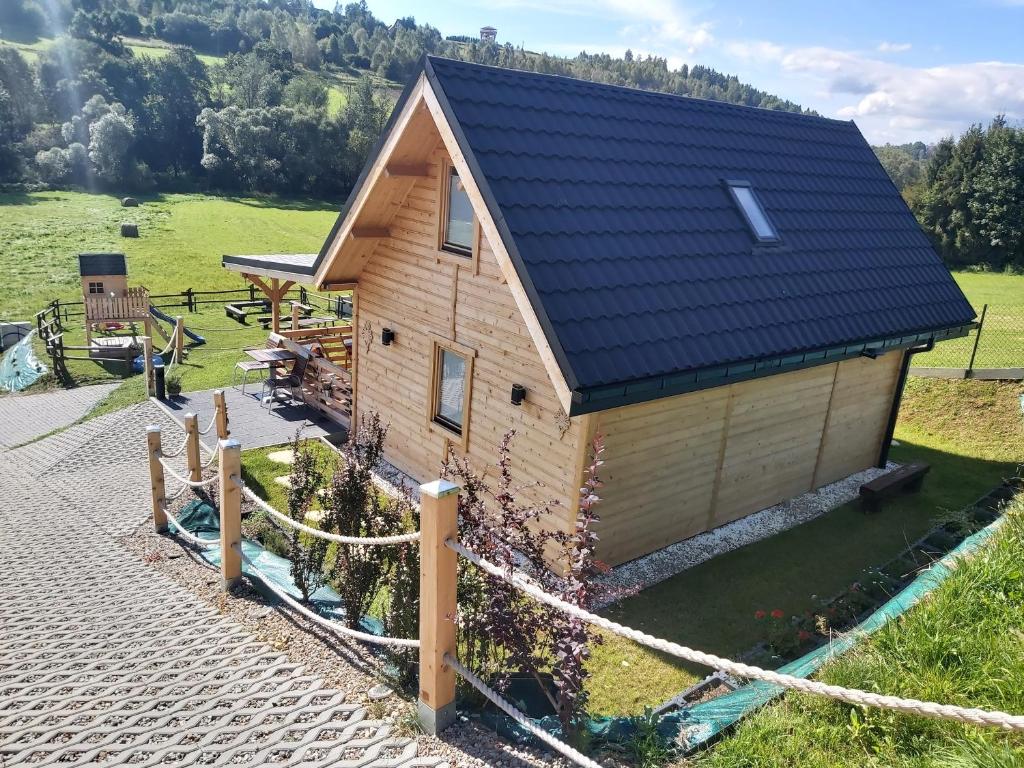 Cette petite maison dispose d'un toit en ardoise et d'une terrasse. dans l'établissement Domek pod Hajdówką, à Jordanów