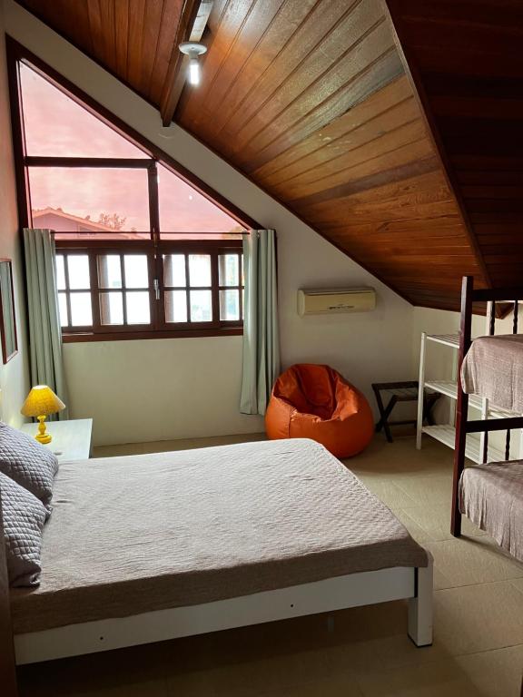 een slaapkamer met een bed en een groot raam bij Townhouse composta por 4 triplex duas suítes a duas quadras do mar in Barra de Ibiraquera