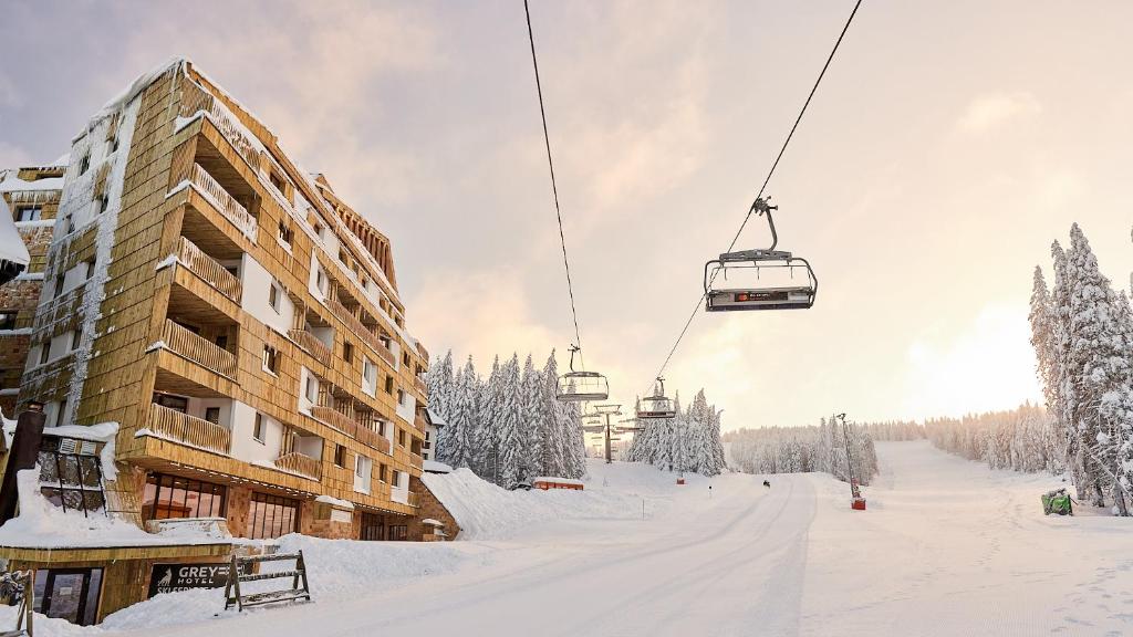 eine Skipiste mit einer Skihütte und einem Skilift in der Unterkunft Grey Hotel Kopaonik in Kopaonik