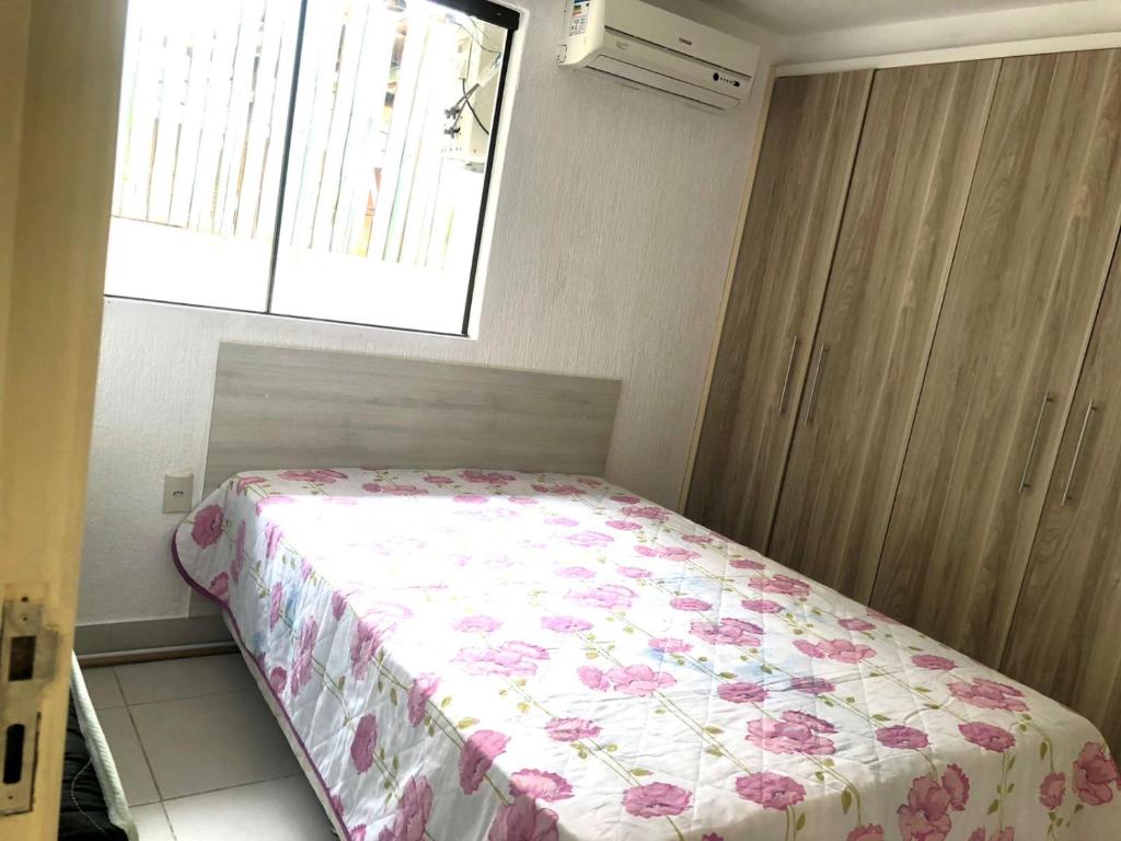 um pequeno quarto com uma cama com um cobertor floral em Casa térrea em Guarajuba para Veraneio em Camassari