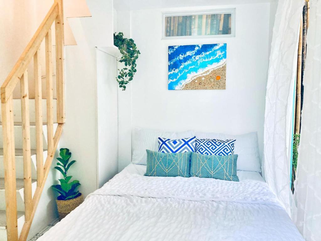 Dormitorio blanco con cama con almohadas azules en Balai Lawaan Charming Sanctuary, en Iloilo City