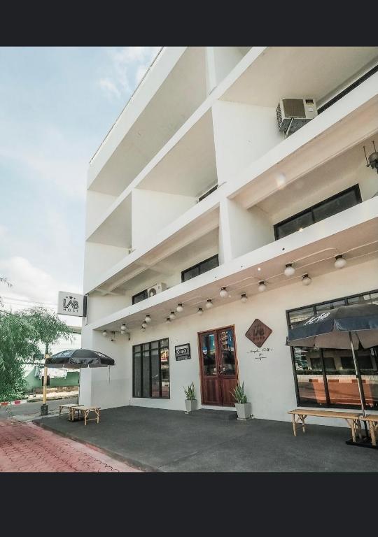 a large white building with two benches in front of it at Labkoff cafe and Hostel in Kanchanaburi City