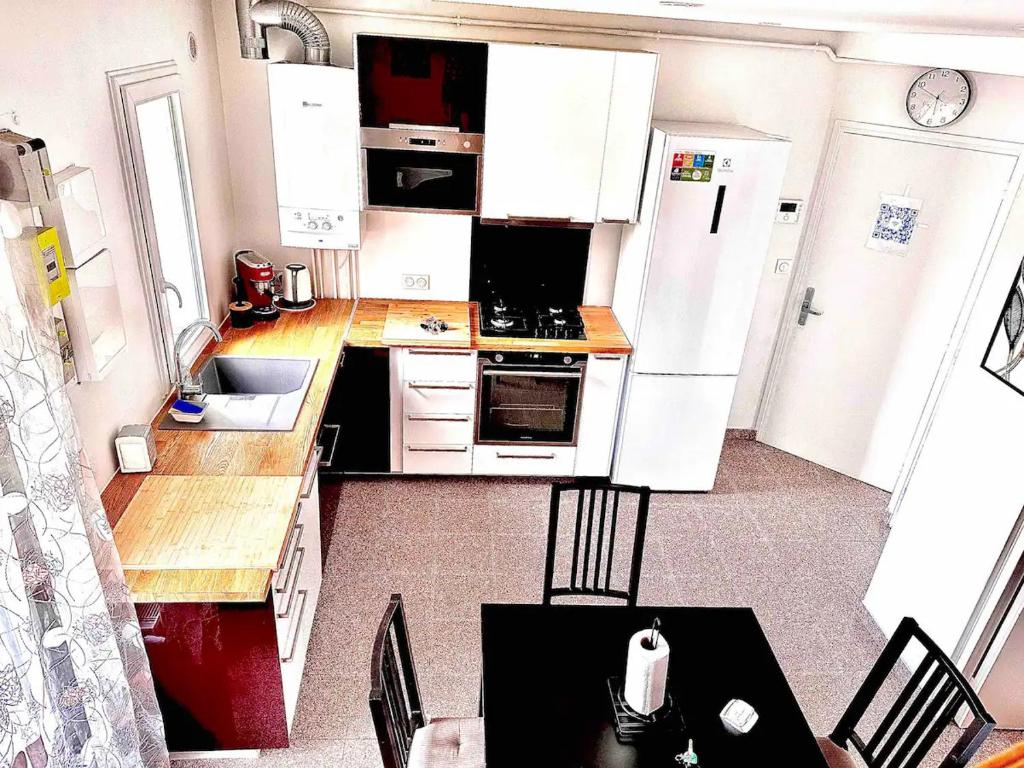 una cocina con electrodomésticos blancos, mesa y sillas en Gheddachi en Gentilly