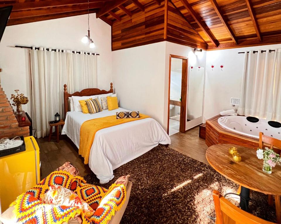 1 dormitorio con cama y bañera en Chalés Recanto da cachoeira, en Monte Verde