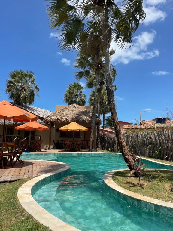 a swimming pool with a palm tree next to a resort at Pousada Vila Tapera in Barra Grande
