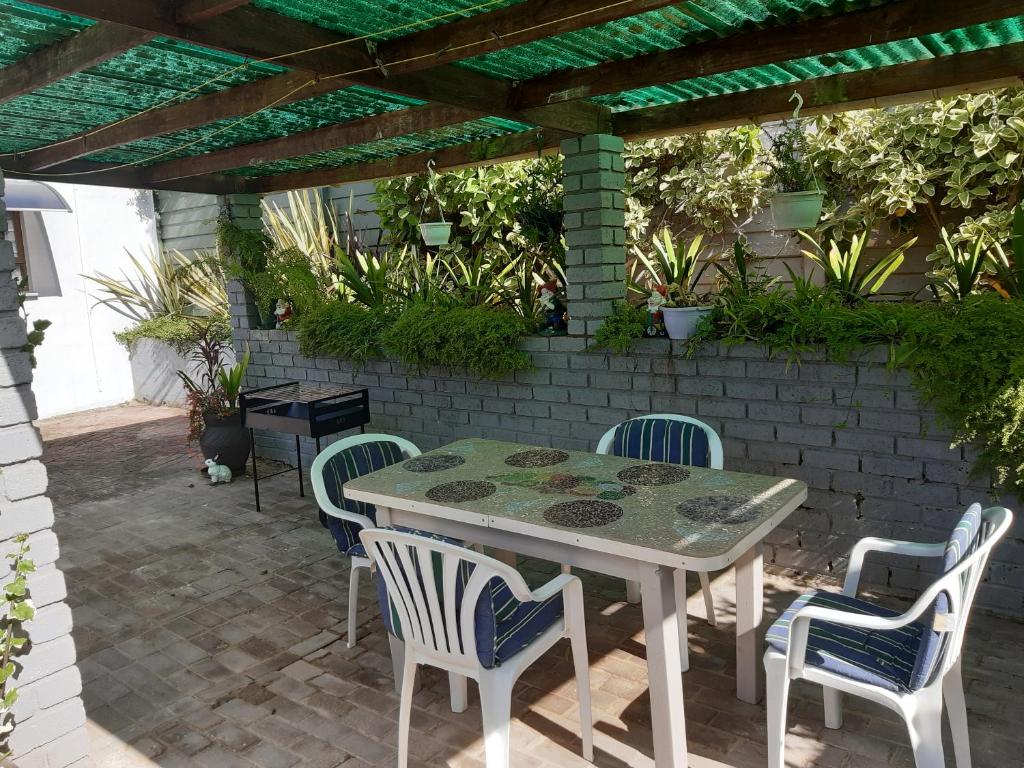 un patio con mesa y sillas bajo una pérgola en Rosies en George