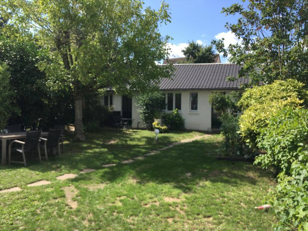 a house with a yard with a tree and a table at Au Tour Des Bois in Le Vésinet