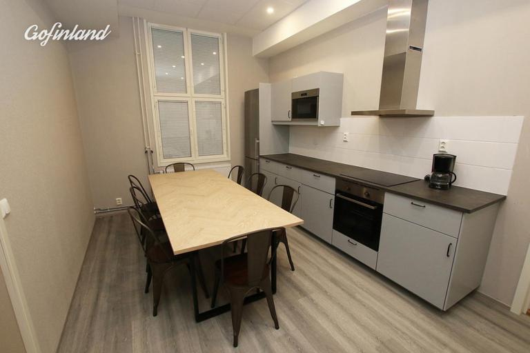 uma cozinha com uma mesa de madeira, uma mesa e cadeiras em Kuukkeli Ivalo Airport Inn em Ivalo