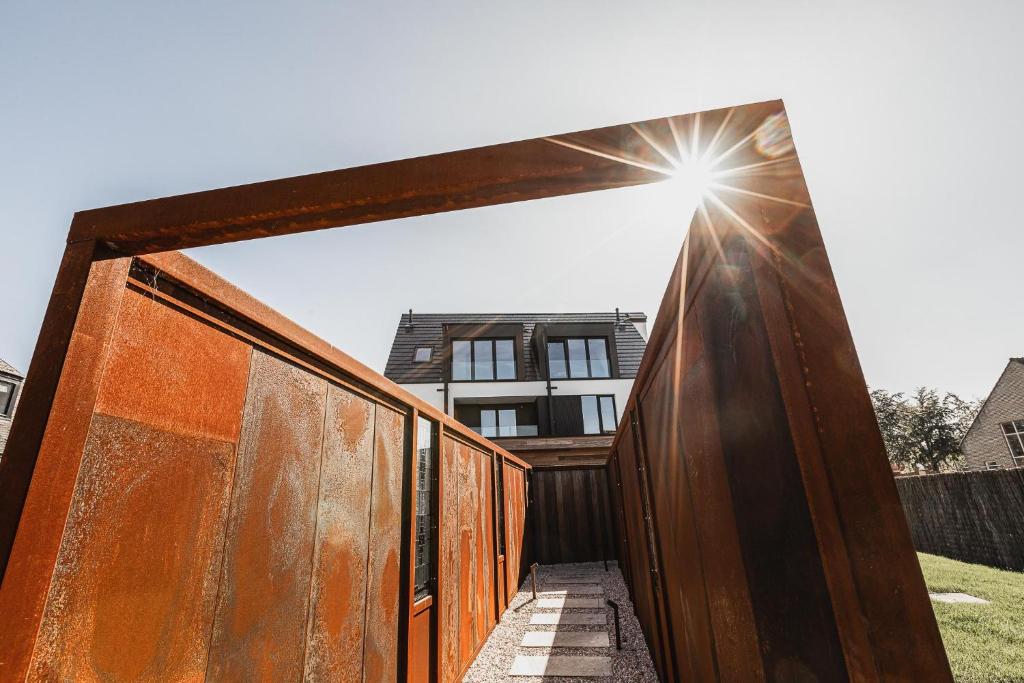 a wooden fence with the sun shining through it at Stay Charmed in Jabbeke