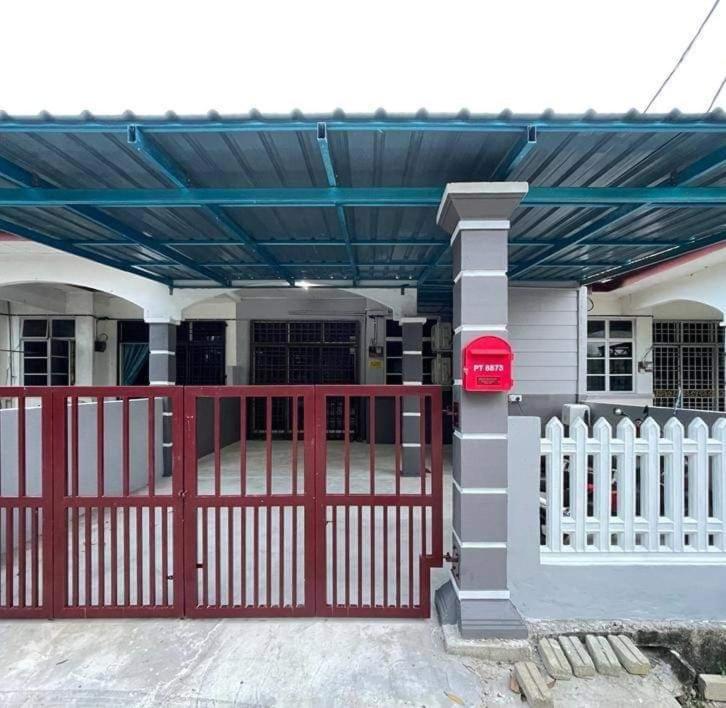 een huis met een rode poort en een hek bij SRI TEGUH HOMESTAY in Tanah Merah
