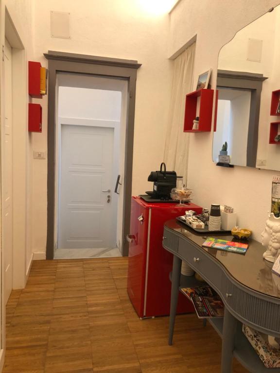 Zimmer mit einer weißen Tür und einem roten Kühlschrank in der Unterkunft DIMOR'A' ROOMS in Pitigliano