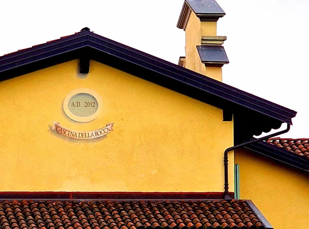 un edificio giallo con un cartello sopra di Cascina Della Rocca a Caselle Torinese