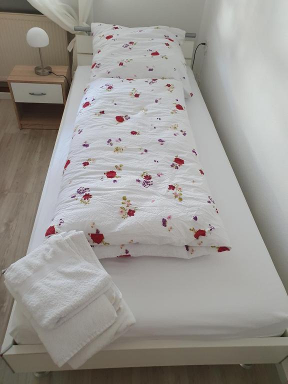 a bed with a white bedspread with flowers on it at Privatzimmer an der Universitätsklinik Mainz. Sehr zentral in Mainz