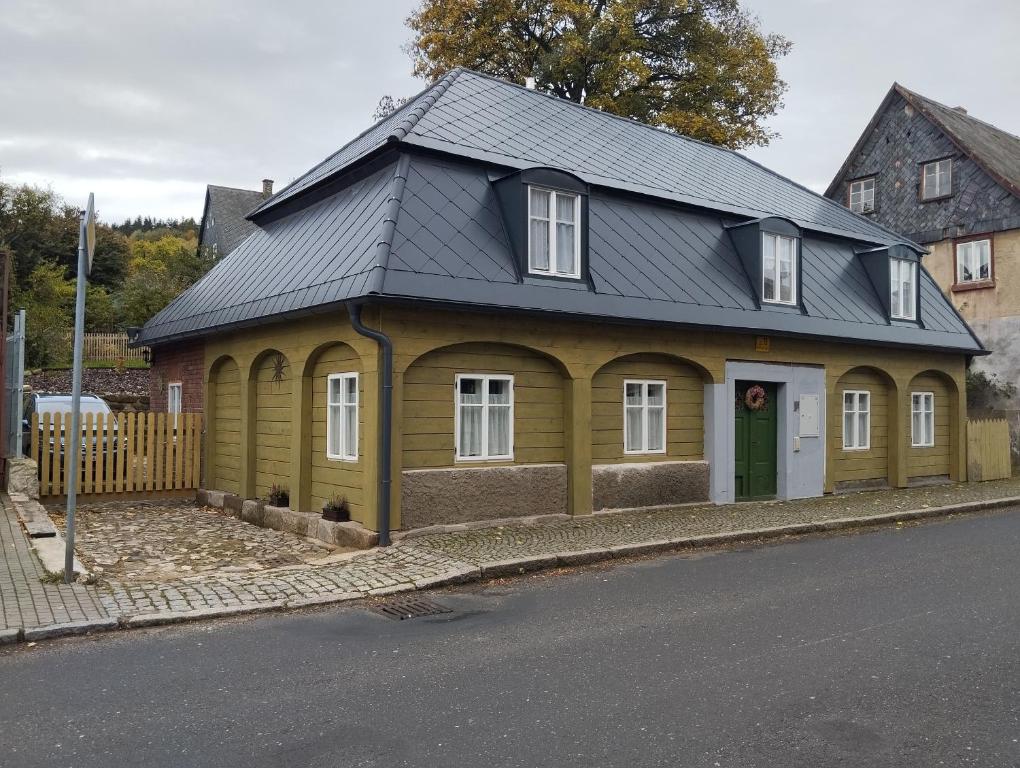 ein gelbes Haus mit schwarzem Dach auf einer Straße in der Unterkunft Chalupa u Markéty in Jiřetín pod Jedlovou
