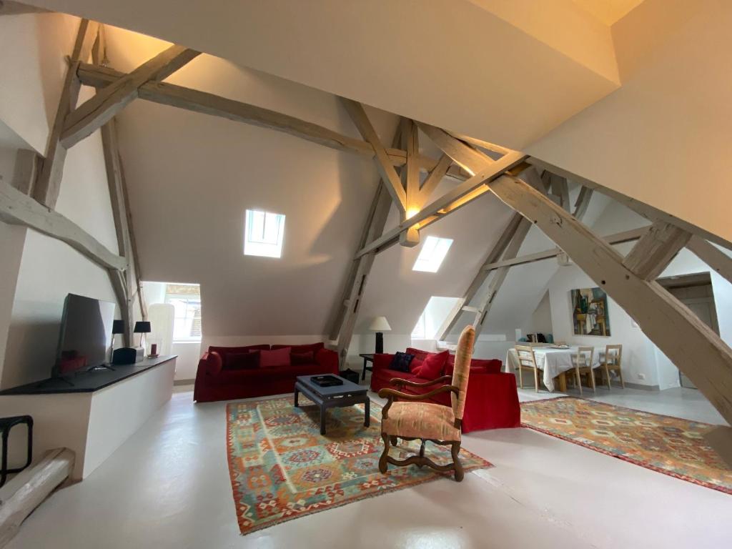 ein Wohnzimmer im Dachgeschoss mit freiliegenden Holzbalken in der Unterkunft Le Loft in Avallon