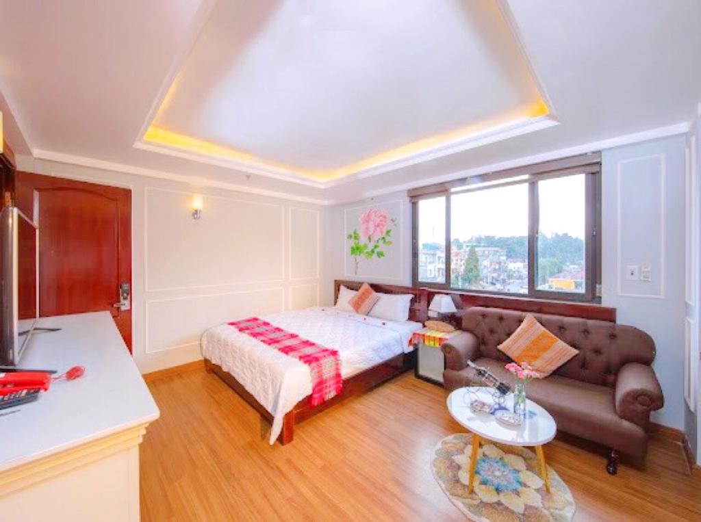 ein Schlafzimmer mit einem Bett, einem Sofa und einem Tisch in der Unterkunft Bing Sapa Hotel in Sa Pa