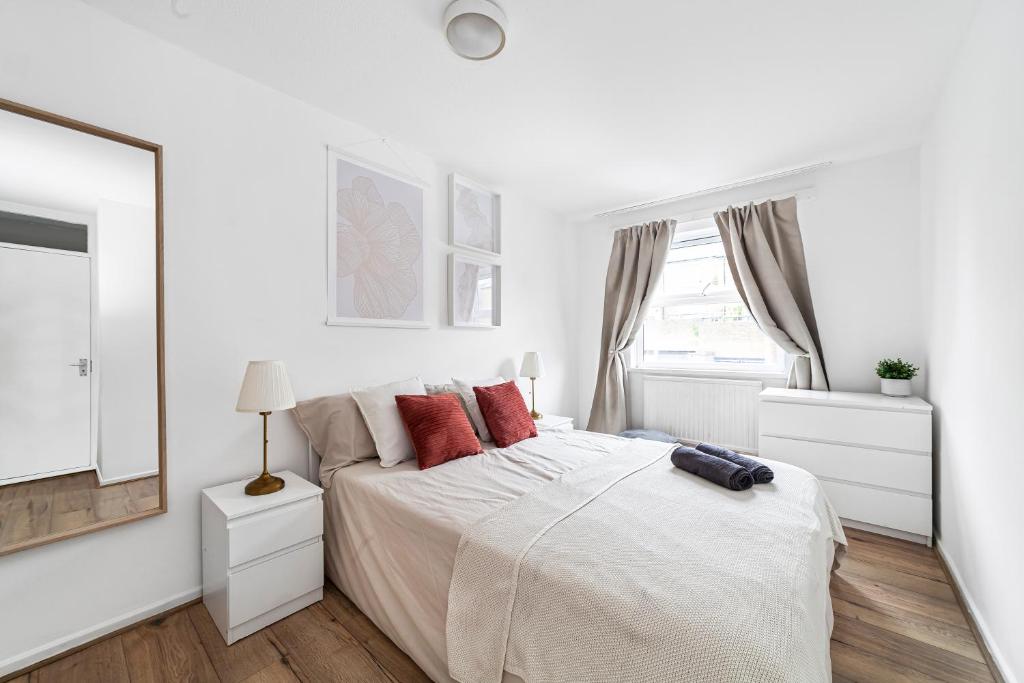 a white bedroom with a large bed and a mirror at Arte Stays - 3-Bedroom Bright House London, Haggerston, Garden, Parking, 8 min walk to Haggerston Station, weekly or monthly stays, serviced accommodation - 7 guests in London