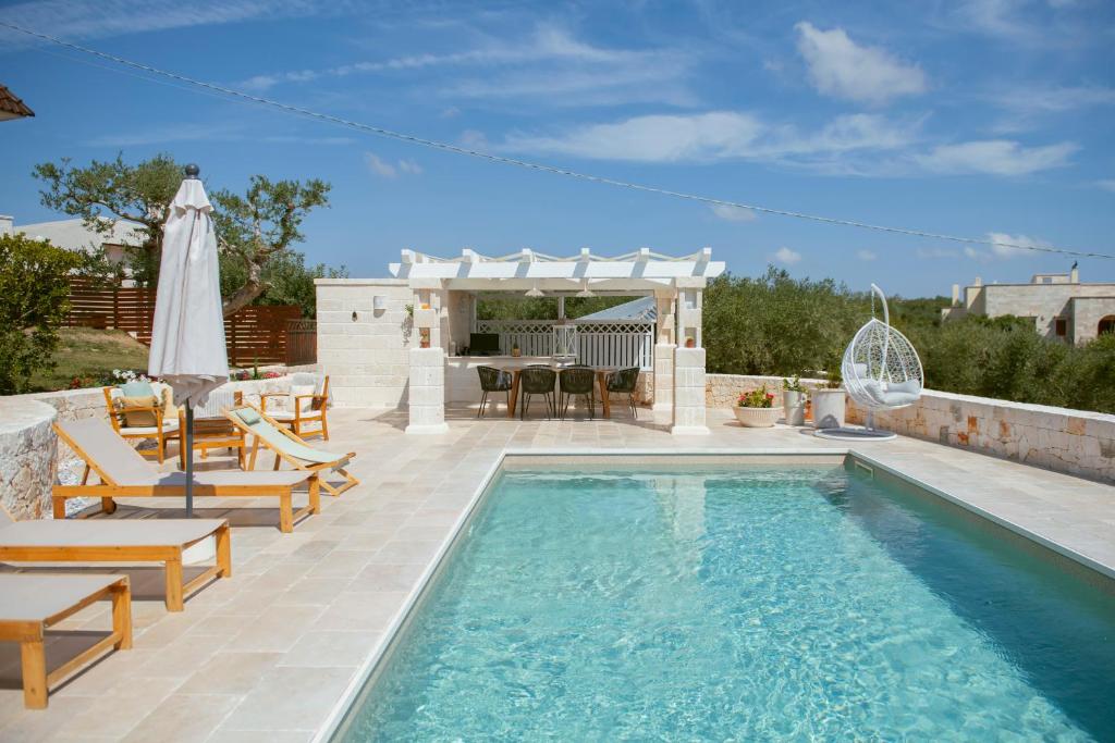 a swimming pool with chairs and a table and a patio at Holiday Home Cosimo in Locorotondo
