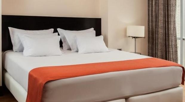 1 dormitorio con 1 cama blanca grande con manta naranja en Hostal Kollarón, en Chachapoyas