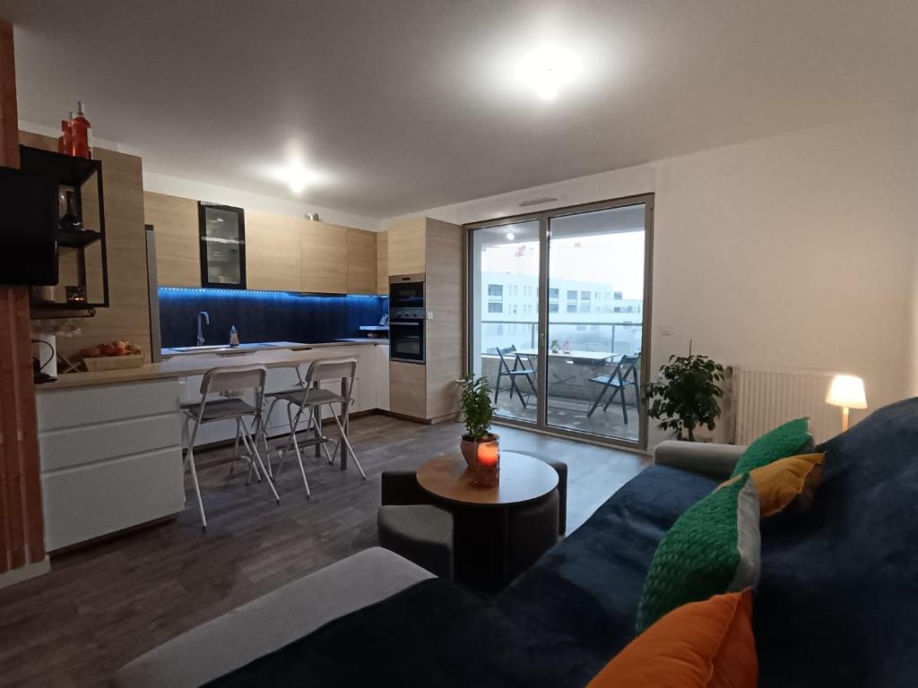uma sala de estar com um sofá azul e uma cozinha em Chambre dans un joli appartement cosy em Bordeaux