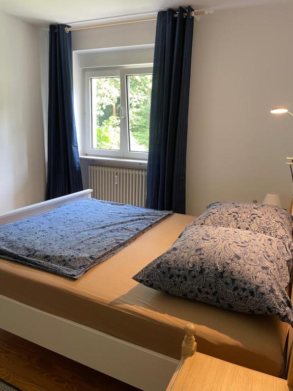 een slaapkamer met een bed met blauwe gordijnen en een raam bij Stadt- Naturnah, Traumblick und Balkon in Baden-Baden