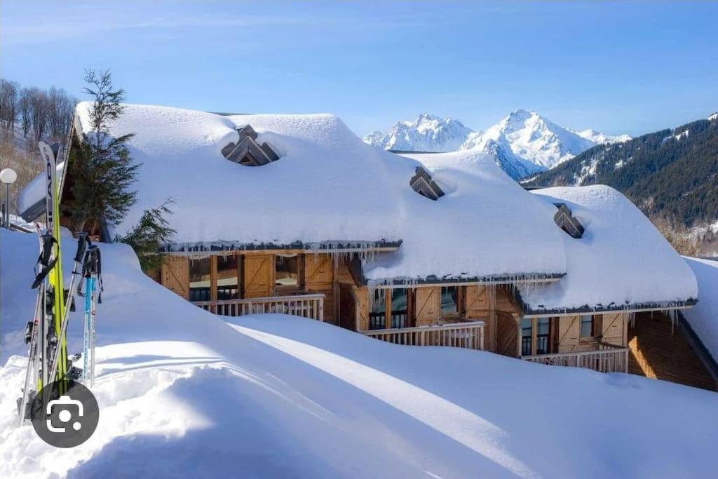 a house covered in snow with skis in front of it at Chalet au pied des pistes in Saint-François-Longchamp