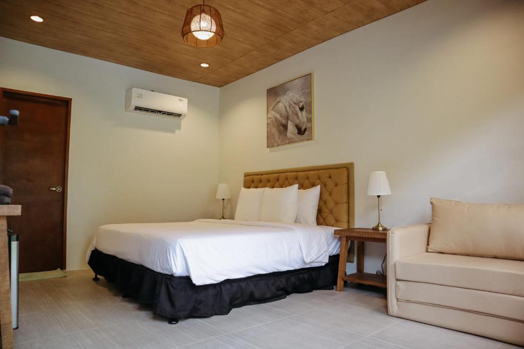 een slaapkamer met een wit bed en een bank bij Swissfinity Beach Resort in Pangubatan