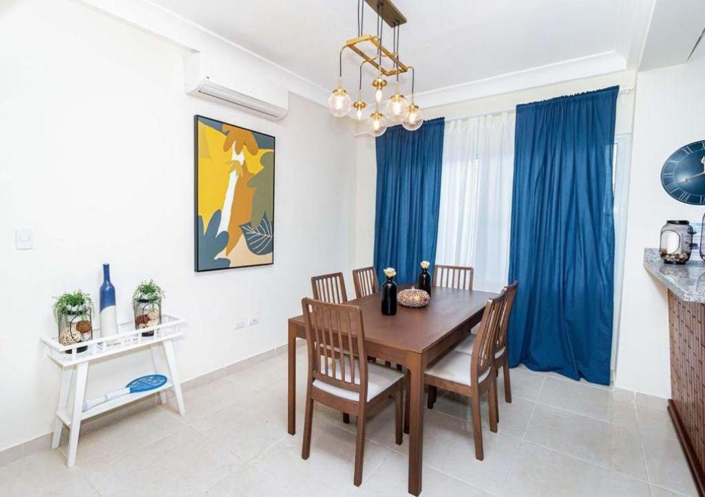 uma sala de jantar com uma mesa de madeira e cortinas azuis em 1R apartamentos in Santo Domingo em Villa Mella