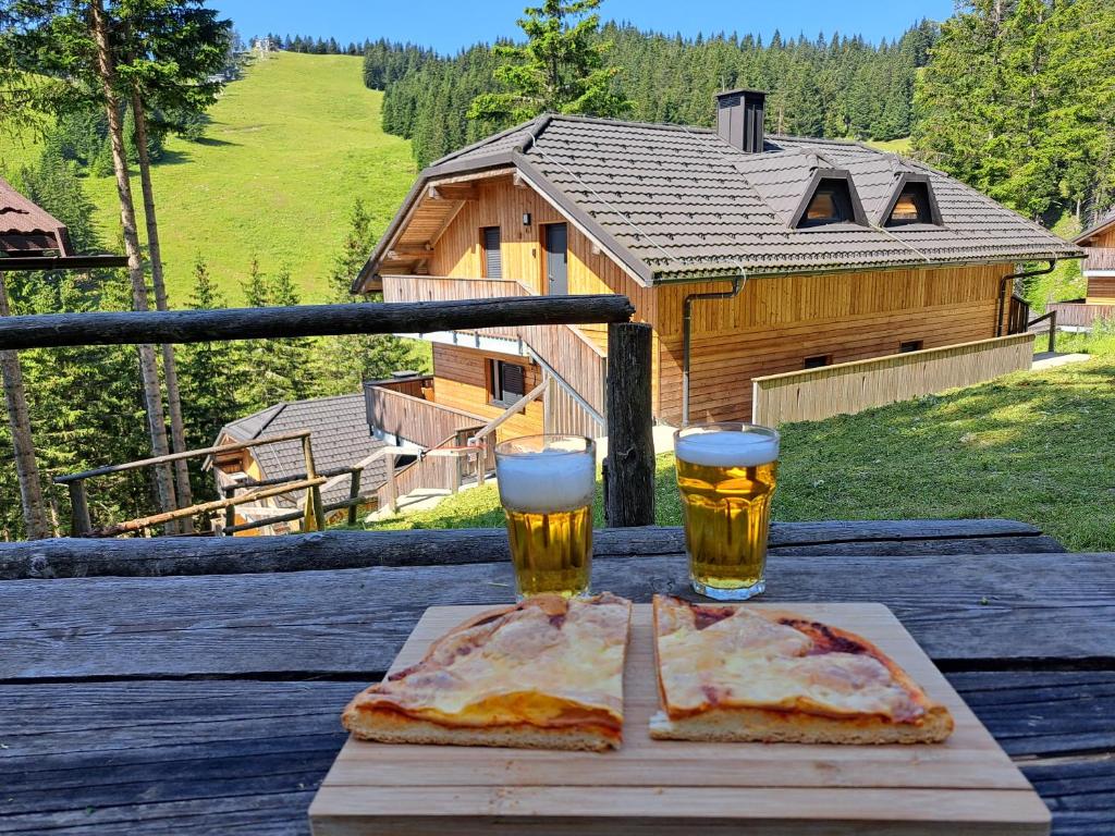two glasses of beer and two slices of pizza on a table at Golte SkiCenter Apartment in Mozirje